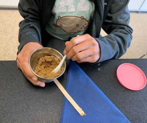 A teenager mixing scrub ingredients, in the teen skincare workshop.